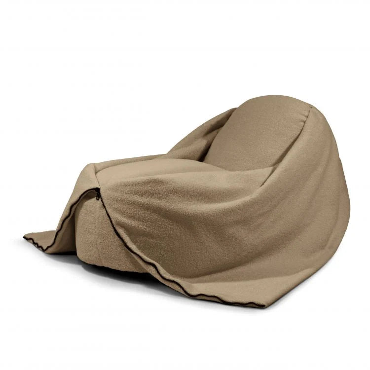 A tan, oversized Bean bag puff de tela borreguito 100×55×60 cm COCOON 100 TEDDY, cubierto con manta a juego y colocado sobre fondo blanco, ofrece comodidad ergonómica para salón, dormitorio o sala de juegos.