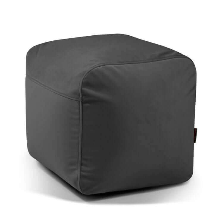 Un compacto y ligero puf cuadrado de terciopelo, 50×50×35 cm, PLUS 50 BARCELONA, ideal como asiento funcional para dormitorio o salón; mostrado en gris oscuro sobre fondo blanco.
