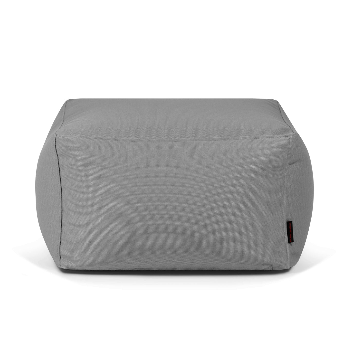 La SOFTBOX PROFUSE es una otomana de tela gris, rectangular, lavable e ignífuga (70×70×40 cm) con bordes lisos y una pequeña etiqueta negra en la parte inferior derecha, que se muestra sobre fondo blanco.
