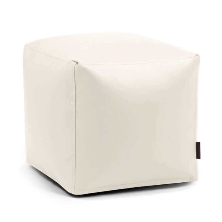 Un puf blanco en forma de cubo. Outside - uso exteriores con bordes lisos y una pequeña etiqueta negra en el lateral, sobre un fondo blanco liso.