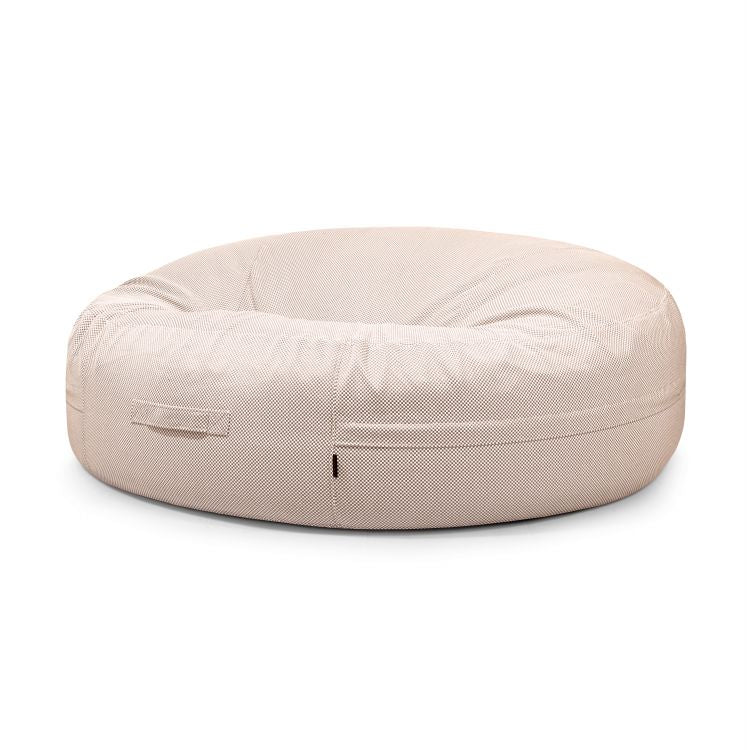 El Bean bag Roll 190 Capri - uso exterior es un gran sillón redondo de bean bag de color beige con funda texturizada y asa lateral, diseñado para ofrecer comodidad y un estilo moderno, presentado sobre un fondo blanco liso.