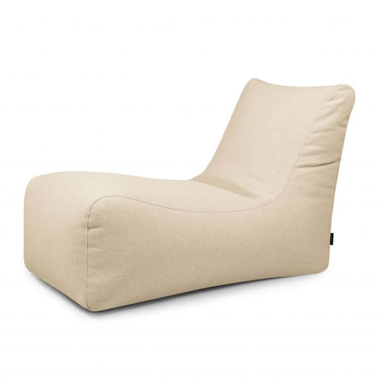 La Bean Bag Lounge Dunes - uso exterior es una moderna chaise lounge de tela beige con asiento bajo y respaldo suavemente curvado, que presenta un diseño minimalista inspirado en un puff, mostrado sobre un fondo blanco liso.