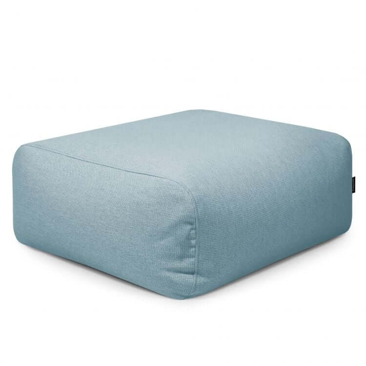 El Puf cuadrado de tejido transpirable y lavable 85×85×38 cm TUBO 80 DUNES, ideal para interior y exterior, presenta un diseño moderno con bordes redondeados y exterior suave, presentado sobre fondo blanco.