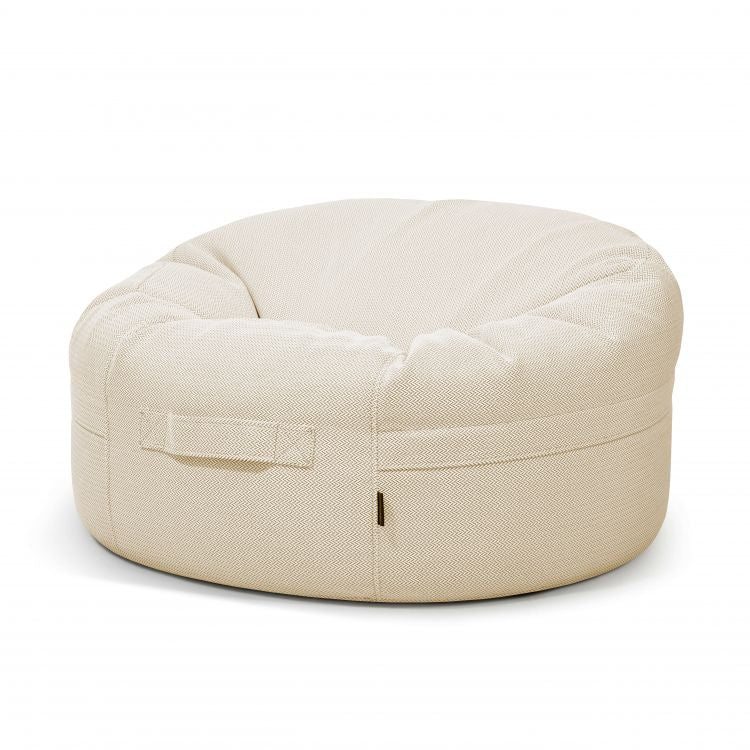 El Bean bag Roll 105 Canaria, diseñado para su uso en exteriores, es una silla redonda en forma de donut de color beige con un asa lateral, que se muestra sobre un fondo blanco y proporciona un asiento ergonómico para cualquier espacio.