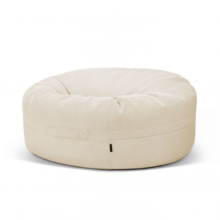 El Bean Bag Roll 135 Canaria - uso exterior es un asiento redondo de color beige con asa cosida y costuras visibles, que sirve como puff elegante y ergonómico para cualquier espacio, perfecto como asiento exterior sobre un fondo blanco liso.