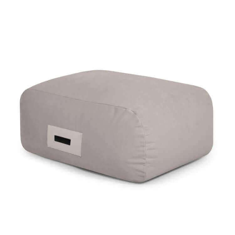 El ChatGPT Plus Puff de foam tapizado en terciopelo 85×68×40 cm SNUG 83 BARCELONA, rectangular y gris claro con asa lateral, ofrece asiento ergonómico y un toque moderno para salón o dormitorio.