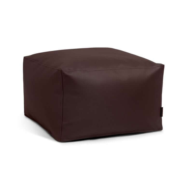 El Pouf Softbox Outside - uso exterior es una otomana cuadrada de cuero marrón oscuro con exterior liso y costuras mínimas, que se muestra sobre fondo blanco.