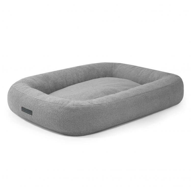 Una Cama para perro de borreguito 100×70×20 cm - DOG BED 100 TEDDY rectangular, gris y afelpada con bordes acolchados en relieve y un suave centro de tela Teddy sobre fondo blanco.