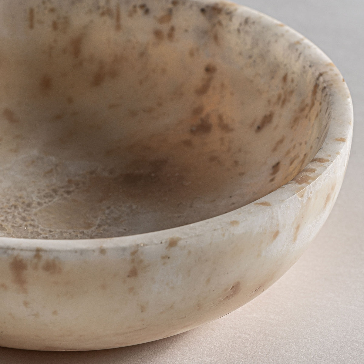 Primer plano del Centro de mesa en ónix artesanal Daily, un cuenco redondo y poco profundo con una superficie lisa y pulida y jaspeado natural marrón y beige, ideal para una decoración interior elegante.