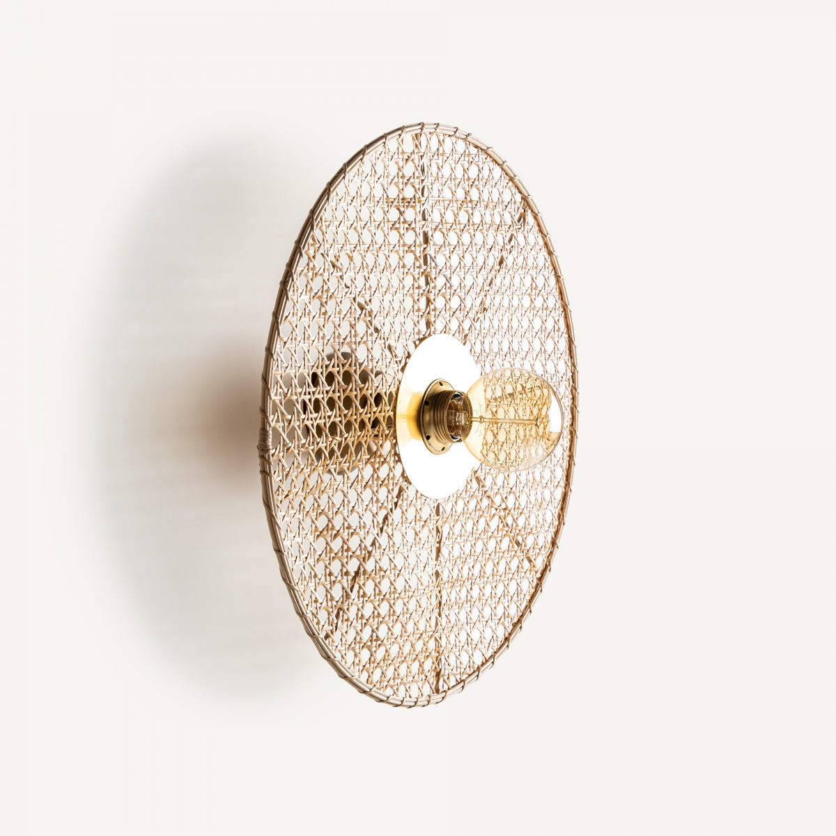 Aplique de pared en hierro y ratán Bellea, con pantalla redonda tejida y bombilla visible, añade un toque vintage art déco; Imagen tomada sobre fondo blanco.