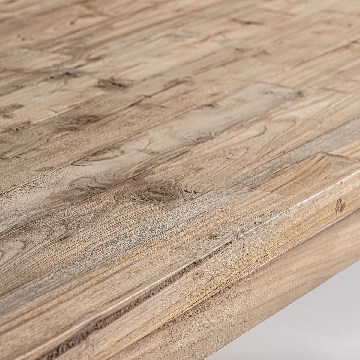 Primer plano de la Mesa de comedor en madera de teka reciclada Lux, que muestra un patrón de vetas de madera natural y diferentes tonos de marrón, que recuerdan al diseño colonial.