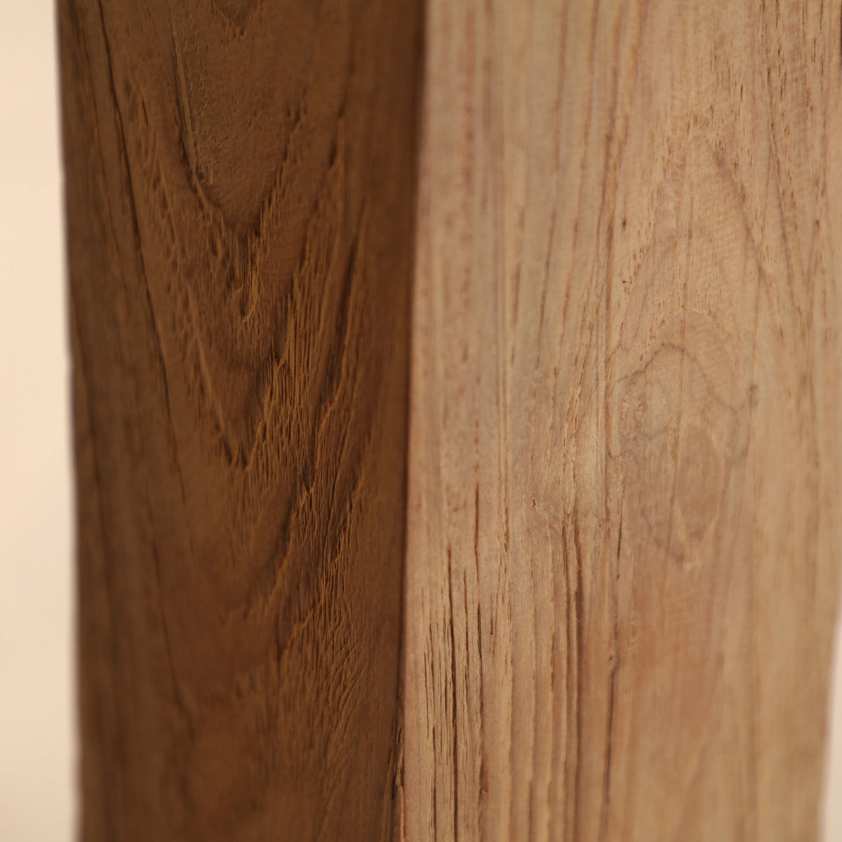 Un primer plano de la Mesa de comedor en madera de teka reciclada Lux muestra una superficie de madera con una sección más oscura y texturizada a la izquierda y una sección más clara y suave a la derecha, agregando elegancia y estilo colonial a cualquier ambiente.