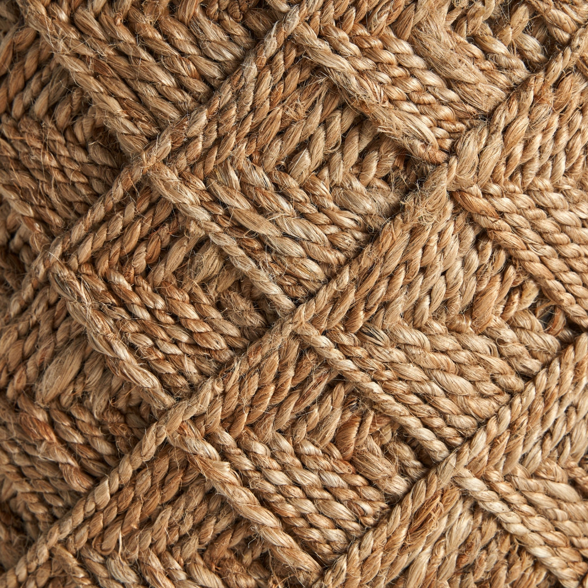 Primer plano del Puff redondo de yute trenzado Elgin, mostrando su patrón texturizado de fibras de yute entrelazadas, formando formas de diamantes entrecruzados en un diseño de estilo vintage.