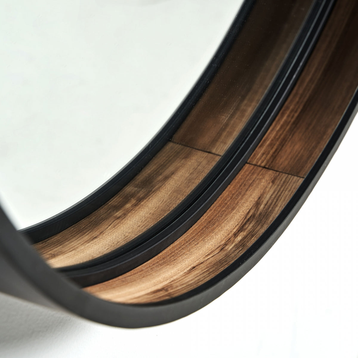 Primer plano del Espejo redondo en hierro negro y DM (100x100 cm) Aimar, con un marco de metal negro y detalles en madera, que refleja la luz para ampliar la percepción del espacio.