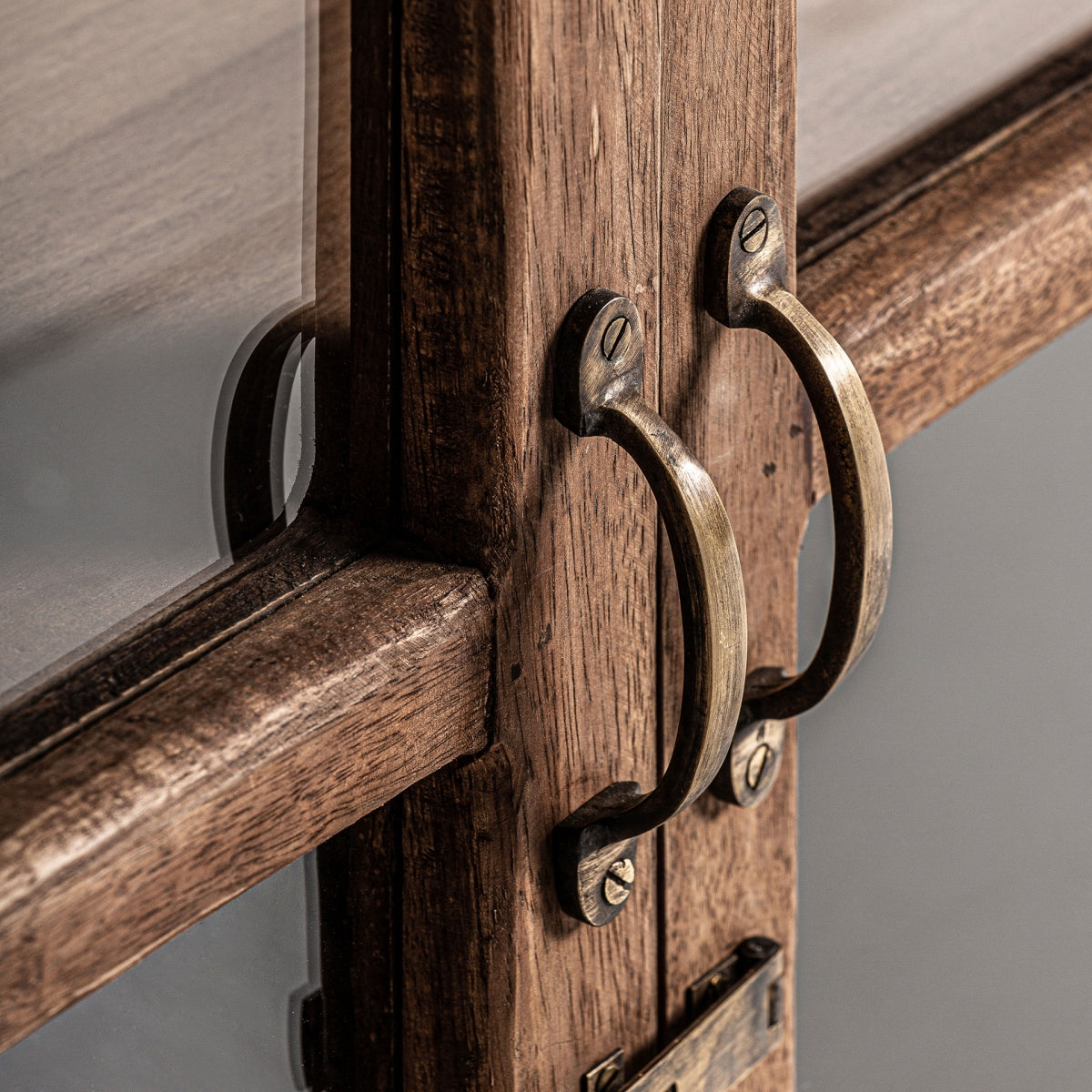 Primer plano de dos manijas de latón en la Vitrina rústica en madera reciclada Jekye, resaltando la textura del metal y la madera de mango reciclada para un ambiente acogedor.