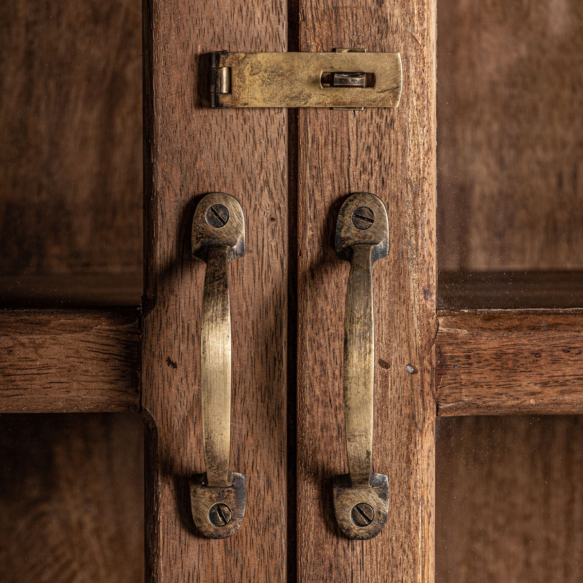 Primer plano de dos manijas de latón y un pestillo deslizante en puertas de gabinetes de madera, elaborados a partir de madera reciclada para la Vitrina rústica en madera reciclada Jekye, agregando un ambiente acogedor a cualquier espacio.