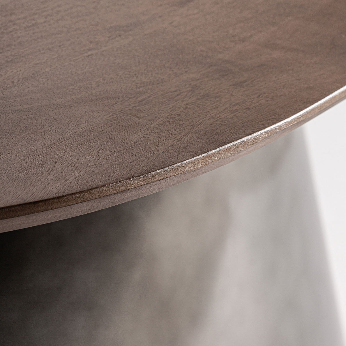 Primer plano de una mesa redonda de madera con borde liso y acabado marrón claro, que recuerda al diseño art déco, sobre la base difuminada de la Mesa de comedor rectangular en madera y acero Warhem.