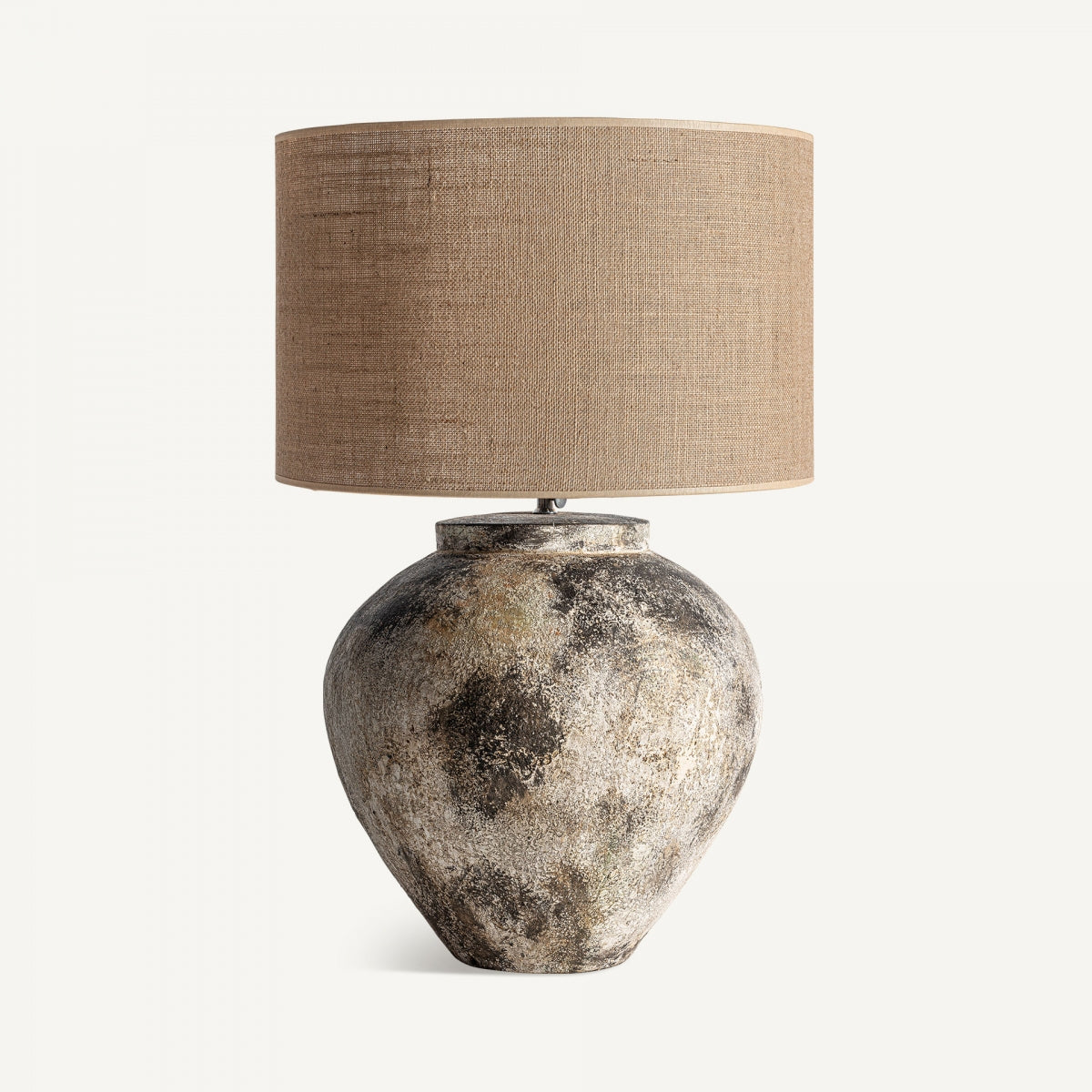 La lámpara de mesa en terracota y yute Kirston, con base texturizada y pantalla cilíndrica marrón, es ideal para aportar un toque rústico y elegante a cualquier ambiente.