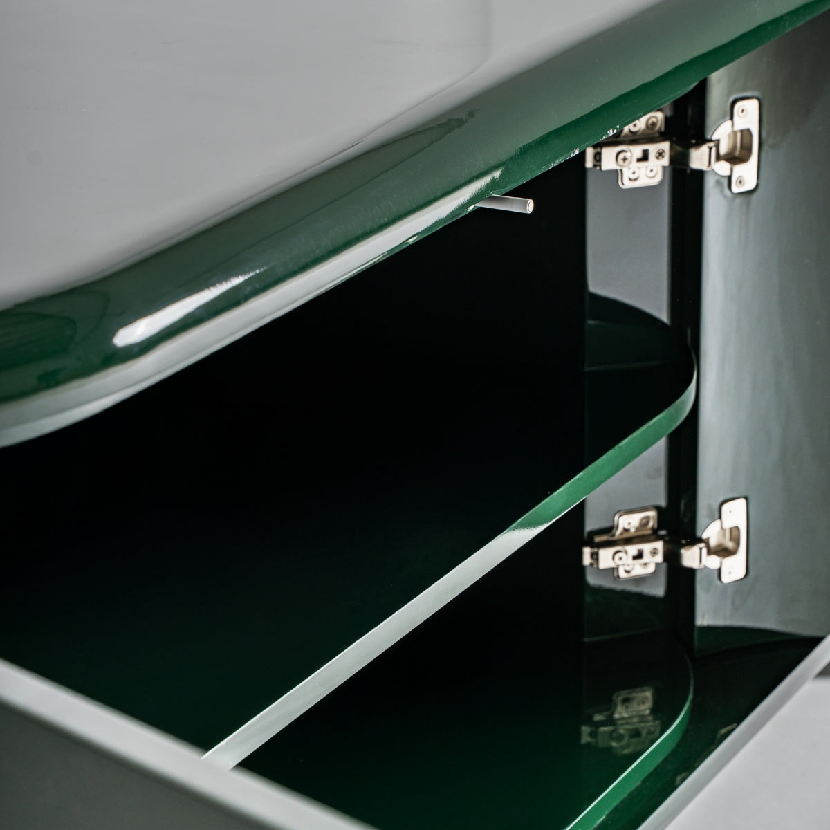 Primer plano de un Aparador Gory abierto en DM verde y acero inoxidable (180x45 cm), con dos estantes interiores y bisagras metálicas en las puertas, un acento Art Déco para los amantes de los muebles exclusivos.