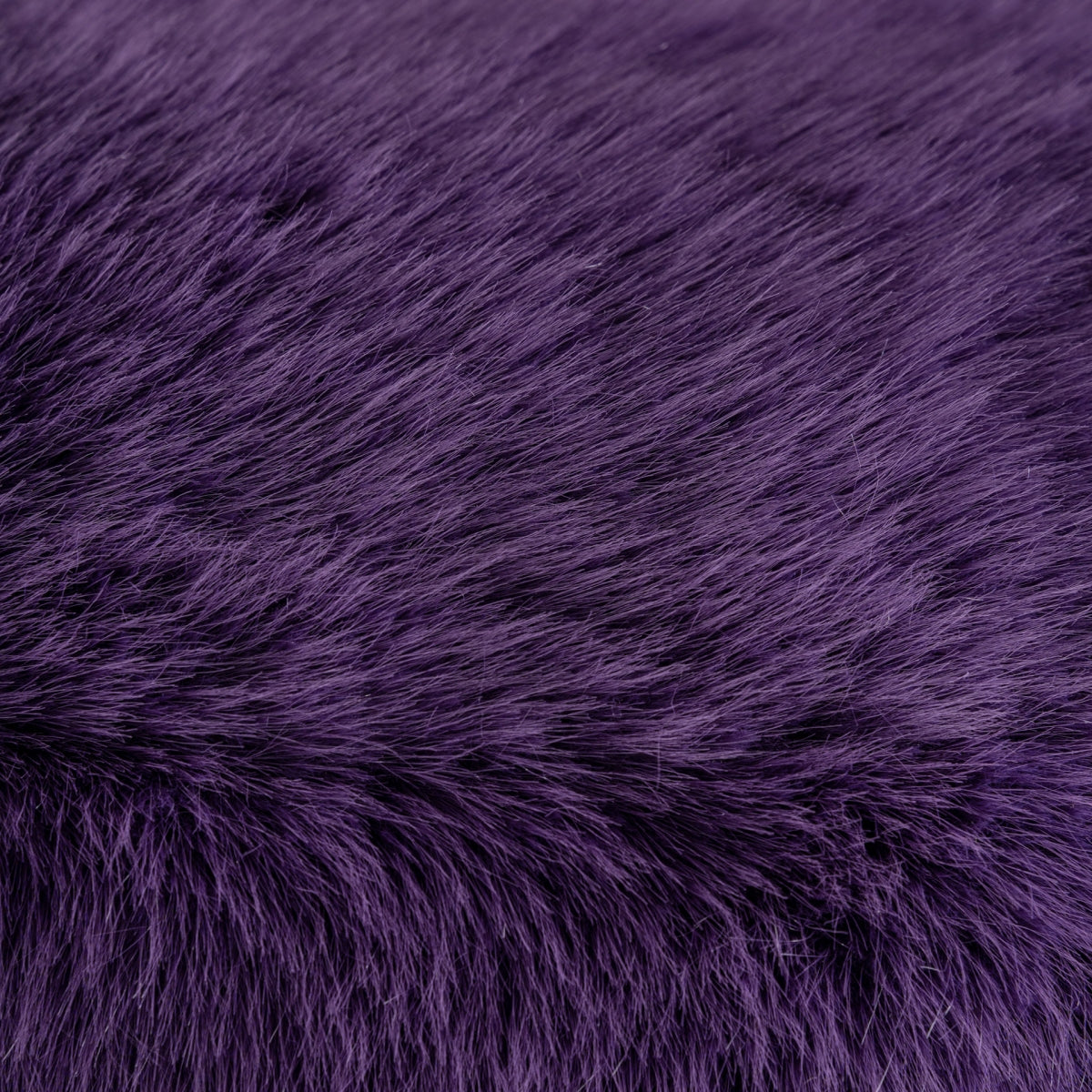 Un primer plano de la textura de piel violeta del Puff redondo tapizado en peluche Tropez revela fibras densas y suaves, ideales para tapicería de felpa.