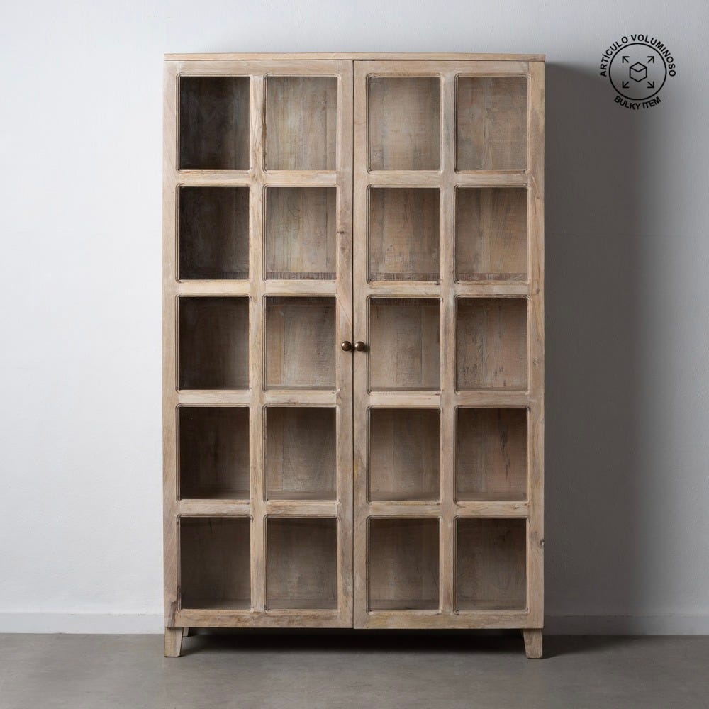 La Vitrina Alta Natural Blanco Rozado Madera de Mango es un mueble alto de madera con un diseño rústico, elaborado con madera de mango. Cuenta con dos puertas con paneles de vidrio, colocadas contra una pared blanca sobre un piso de concreto. El lado superior derecho tiene un logotipo.