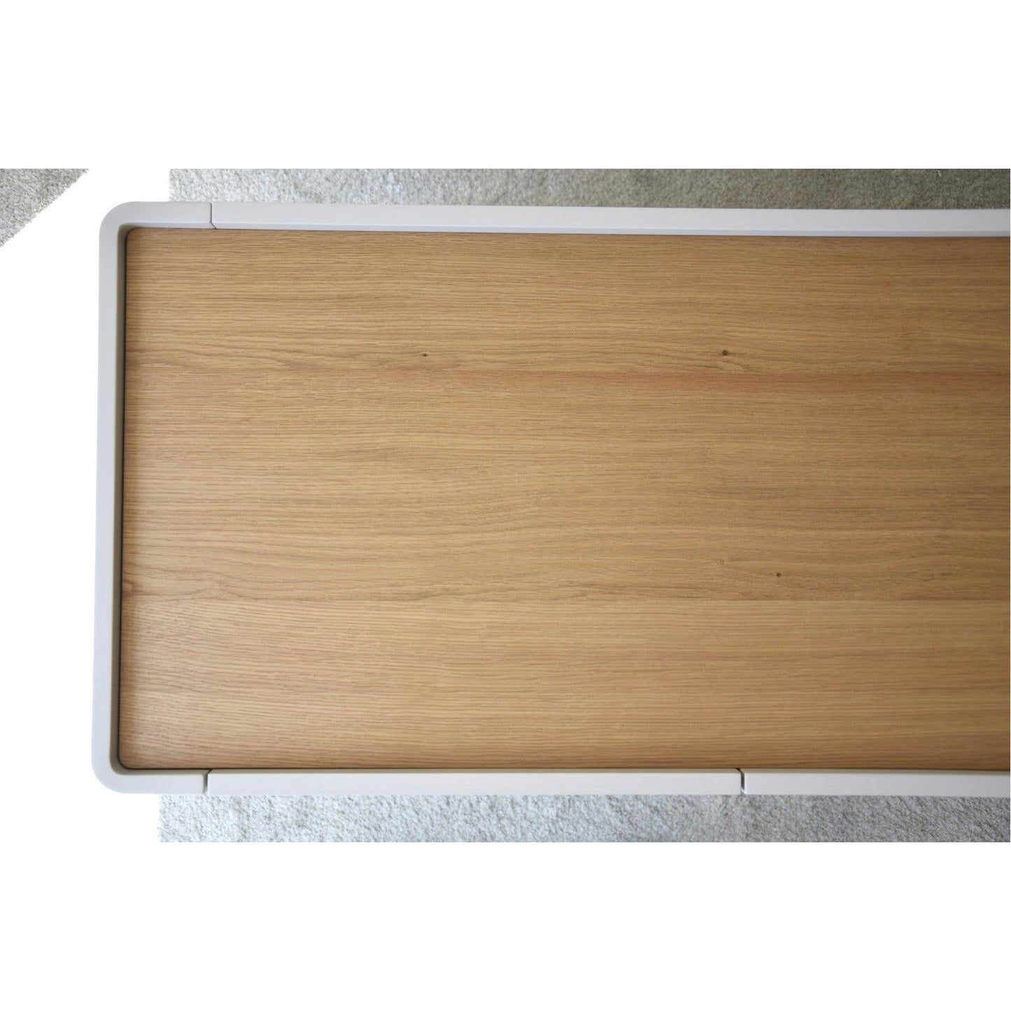 El Aparador bajo Gris Arena y Madera de Roble Elegance presenta una superficie rectangular de color marrón claro enmarcada en blanco, ofreciendo un diseño contemporáneo elaborado a partir de roble fino, visto desde arriba.