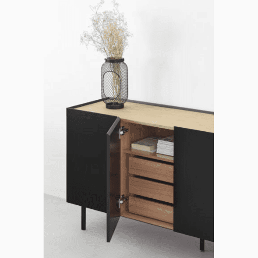 El Aparador bajo con Puertas Arista 4P3C presenta puertas abiertas que revelan estantes y libros dentro de su interior de madera, lo que encarna el diseño moderno. Este versátil gabinete negro está adornado con un jarrón decorativo de flores secas en la parte superior.