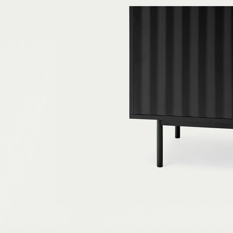 El Aparador bajo en madera y DM Sierra 2P4C en negro, con ranuras verticales y patas esbeltas sobre un fondo pálido, ejemplifica el diseño moderno e industrial.