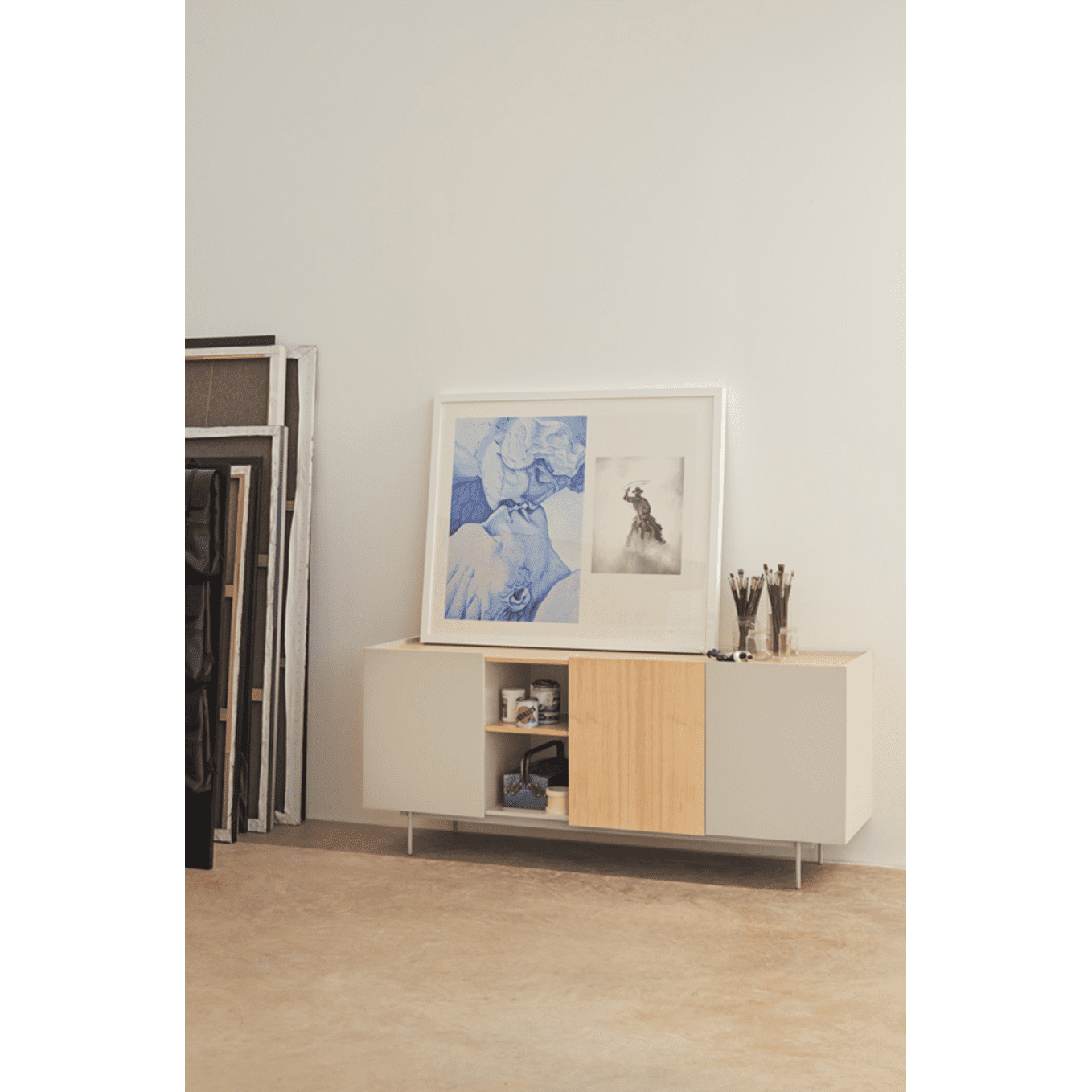 El aparador moderno Otto 3P3C, con su diseño elegante, cuenta con estantes abiertos para cuadros y pinceles, lo que proporciona un almacenamiento versátil. Los cuadros se apoyan contra la pared, lo que realza el ambiente artístico del estudio.