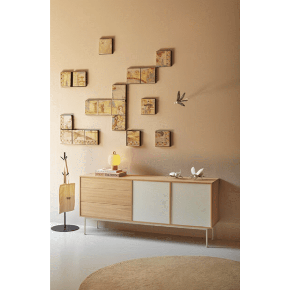 La moderna sala de estar muestra el Aparador moderno Yoko 2P3C, un aparador de madera con un diseño industrial moderno. Presenta arte de pared abstracto, una lámpara amarilla y pájaros decorativos. Una alfombra redonda beige completa el estilo y ofrece soluciones de almacenamiento eficientes.