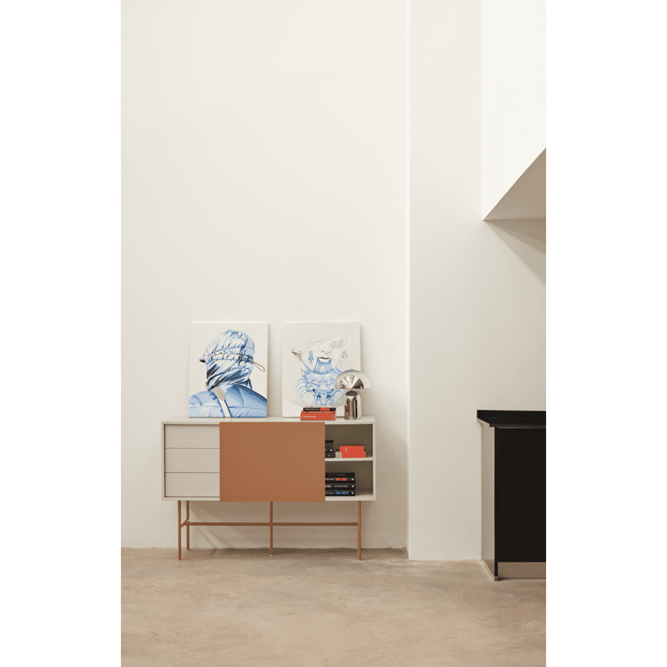 El Aparador moderno con Puerta Corredera Nube 1P3C, que encarna el diseño minimalista de la Colección Nube, tiene cajones, estantes, una elegante puerta corrediza y se apoya contra una pared blanca adornada con dos obras de arte enmarcadas y una pequeña lámpara metálica en la parte superior.