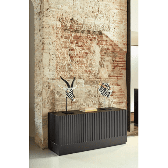 Una pared de ladrillos texturizados con una consola negra y dos bustos de cebra reflejan la arquitectura clásica. Esta configuración puede incluir un Aparador moderno con puertas Doric 3P3C para mayor almacenamiento y organización.