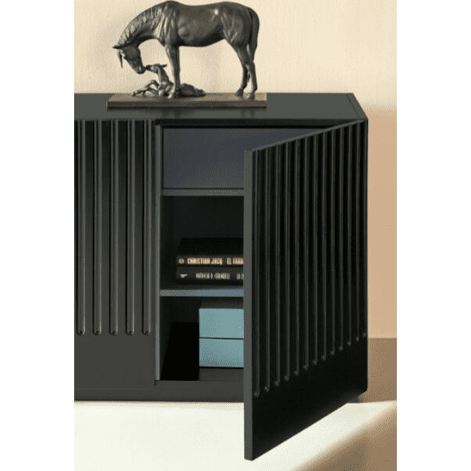 Una puerta abierta en el elegante armario negro, Aparador moderno con puertas Doric 4P4C, muestra un almacenamiento organizado de libros y objetos preciados. Una llamativa escultura de un caballo reposa sobre la parte superior, realzando su diseño clásico inspirado en la columna dórica con una elegante sofisticación.