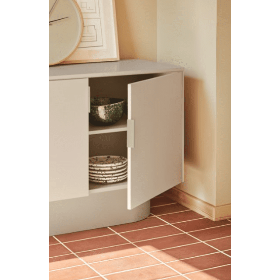 El aparador moderno con puertas Totem 4P3C ofrece un almacenamiento eficiente para utensilios de cocina como cuencos y platos, resaltando un aspecto sutil pero refinado contra un piso de baldosas y una pared de color crema.