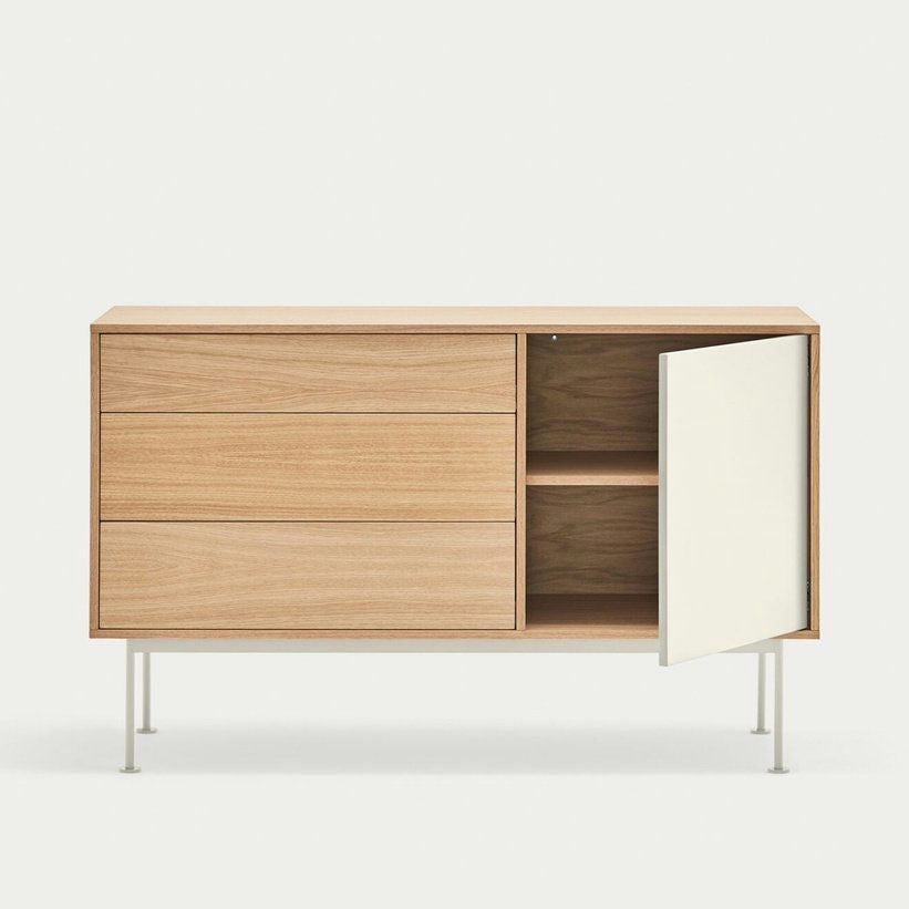 El Aparador moderno pequeño Yoko 1P3C es un mueble de madera con tres cajones cerrados en el lado izquierdo y una puerta abierta en el lado derecho que revela dos estantes. Cuenta con almacenamiento eficiente y un diseño moderno con estética minimalista y elegantes patas blancas.