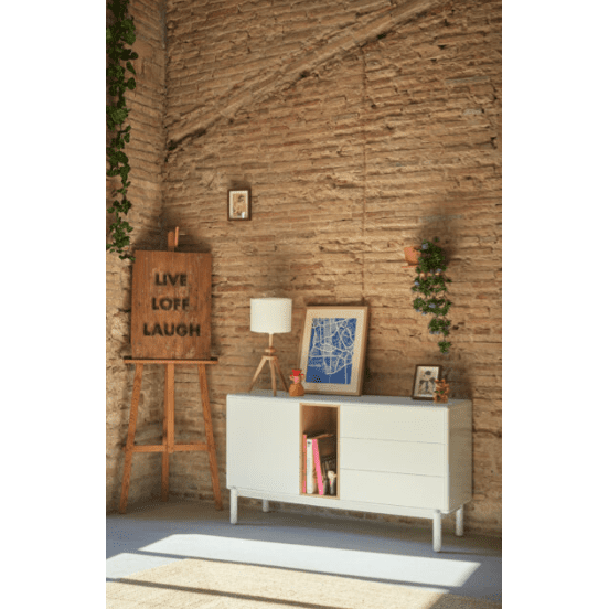 Una habitación con paredes de ladrillo presenta un tema de diseño escandinavo con el Aparador Pequeño con Cajones Corvo 1P3C, un caballete que muestra