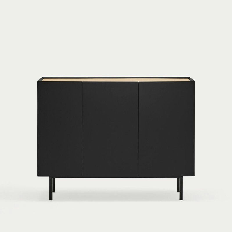 El Aparador pequeño con Puertas Arista 3P3C es un mueble negro de tres puertas con un diseño moderno minimalista, que se apoya sobre patas altas sobre un fondo liso.