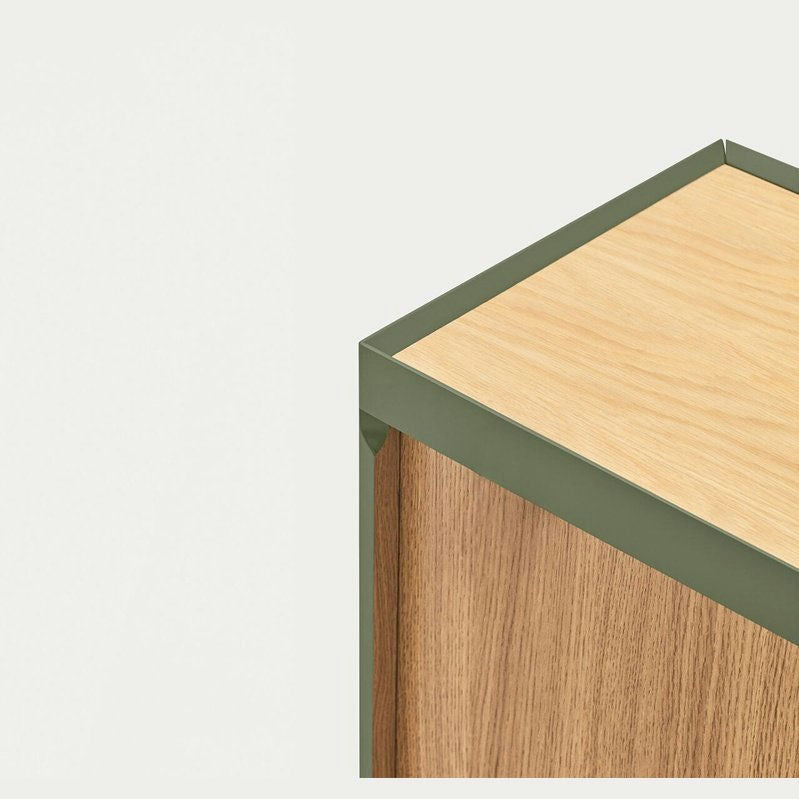 Vista de esquina de Aparador pequeño con Puertas Arista 3P3C, un pequeño gabinete de madera con borde de metal verde que agrega un diseño contemporáneo sobre un fondo claro.