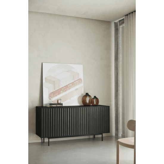 Una habitación minimalista muestra un Aparador pequeño con Puertas Sierra 3P3C negro, adornado con dos jarrones y una pintura abstracta inclinada. Las paredes neutras y las cortinas transparentes completan la decoración industrial moderna.