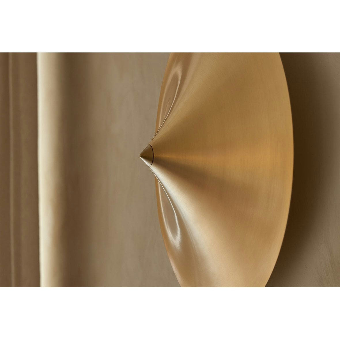 Una vista de cerca del Aplique de pared Hat, una lámpara de pared metálica en forma de cono con una textura suave sobre una superficie clara, muestra una iluminación minimalista.