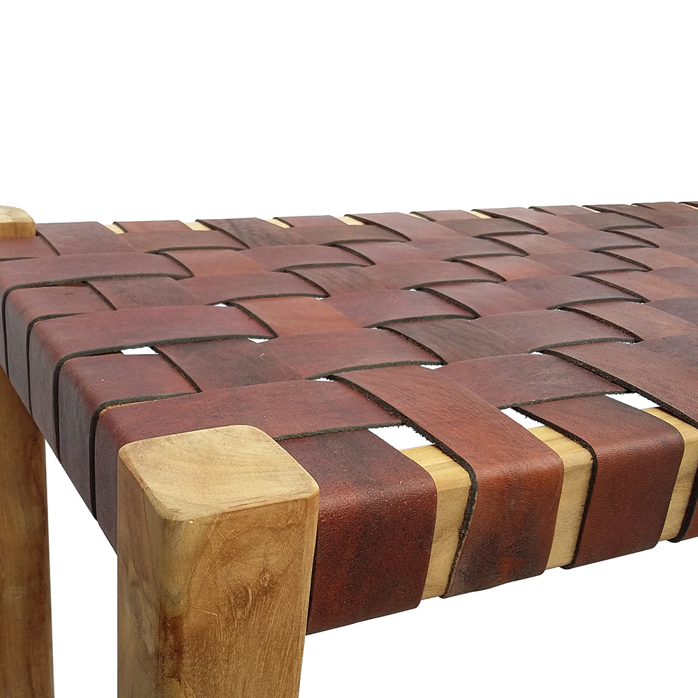 La Banqueta en Madera de Teca y Cuero Zoe Brown (120 cm) combina teca natural y asiento de cuero marrón, destacando su elegante acabado rústico en la esquina y la superficie superior.