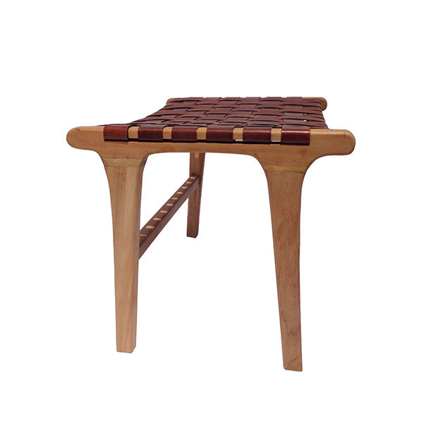 La Banqueta de Madera de Teca y Cuero Zoe Brown (62 cm) cuenta con una robusta estructura de madera de teca, cuatro patas y un asiento de cuero entretejido. Se muestra aquí sobre un fondo blanco.