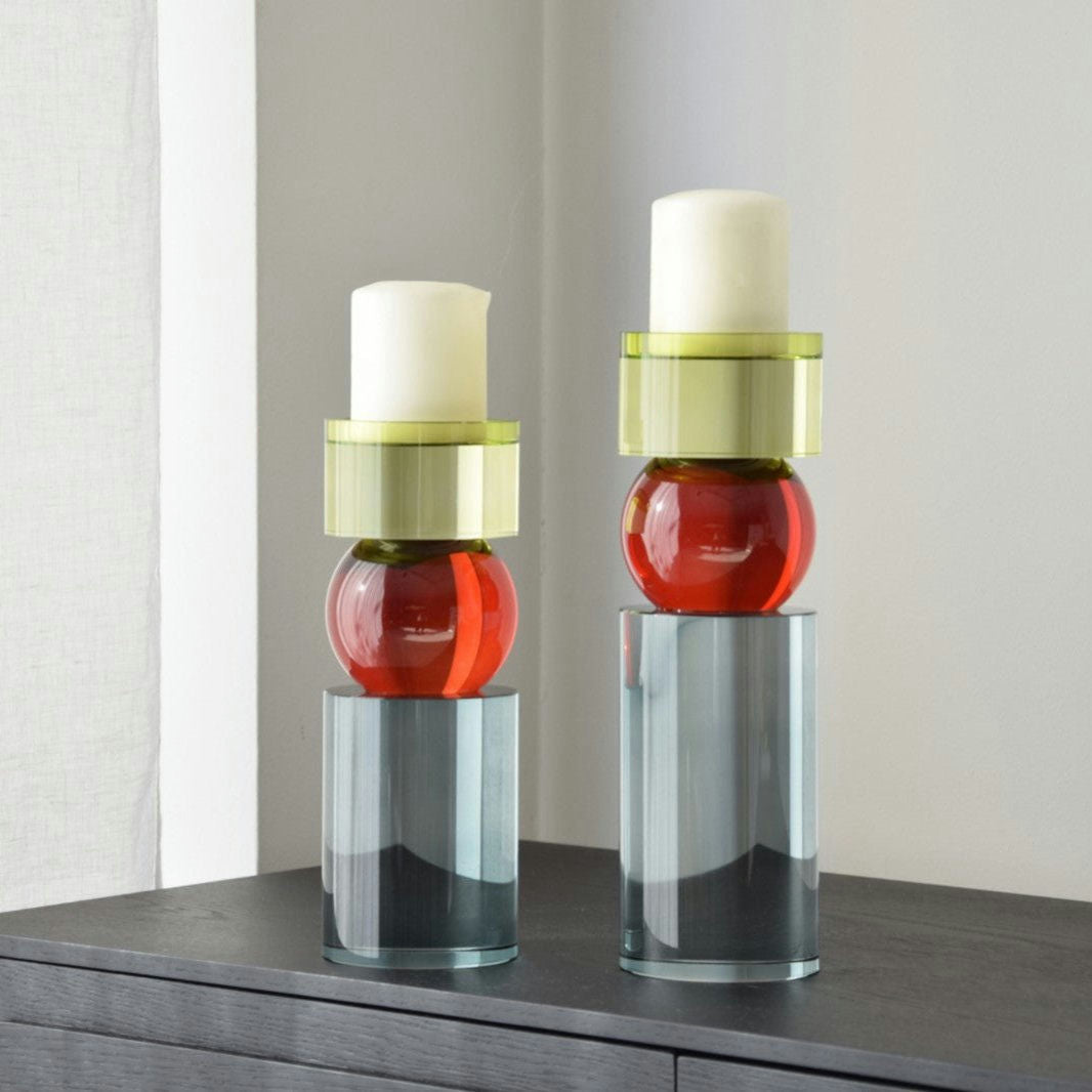 Los candelabros Cristal Color Cilindro, con secciones de vidrio cilíndricas y esféricas apiladas y velas blancas, forman una impresionante pieza central sobre la madera oscura. Su diseño contemporáneo combina a la perfección con los interiores modernos.