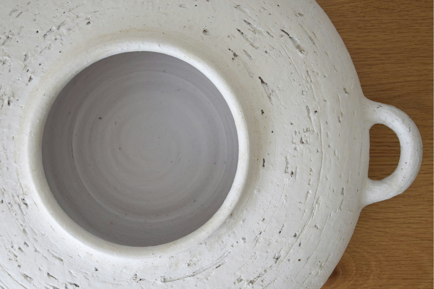 Vista superior del Centro de Mesa Cerámica Ilda en Blanco Pátina con superficie texturizada y un solo tirador sobre mesa de madera, perfecto como centro de mesa artesanal.