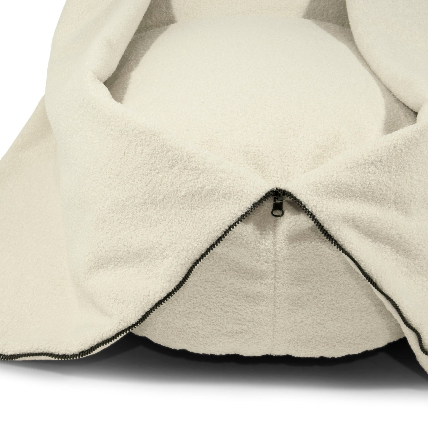 Un primer plano de la funda con cremallera de tela borreguito color crema, parcialmente abierto y mostrando el suave cojín del puff bean bag COCOON 100 TEDDY (100×55×60 cm), ideal para máxima comodidad en salón, dormitorio o sala de juegos.