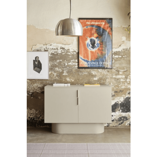 Una habitación minimalista cuenta con una Cómoda en MDF beige con 2 Puertas Totem 2P para un almacenamiento eficiente, combinada con dos carteles enmarcados en una pared texturizada y rematada con una elegante lámpara colgante metálica.