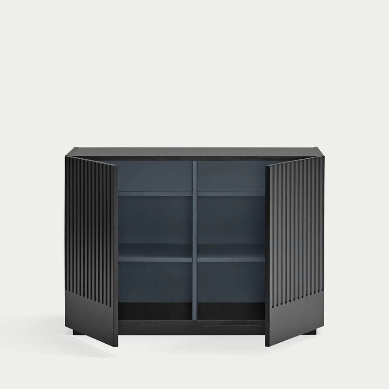 La Cómoda en MDF con 2 Puertas y 2 Cajones Doric 2P2C cuenta con puertas abiertas de lamas negras y dos estantes interiores, proporcionando almacenamiento inteligente con un diseño minimalista sobre un fondo liso y claro.