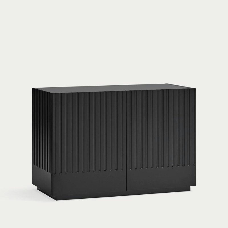 Una Cómoda rectangular negra en MDF con crestas verticales en el frente y los lados, que muestra un diseño minimalista, sobre un fondo claro y liso.