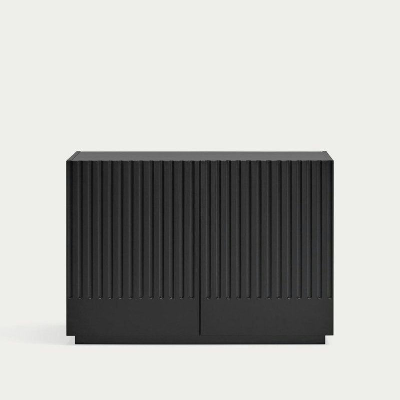 La Cómoda en MDF con 2 Puertas y 2 Cajones Doric 2P2C es un mueble rectangular negro con ranuras verticales y un diseño minimalista. Fabricado con MDF duradero, ofrece un almacenamiento inteligente sobre un fondo claro y sencillo.