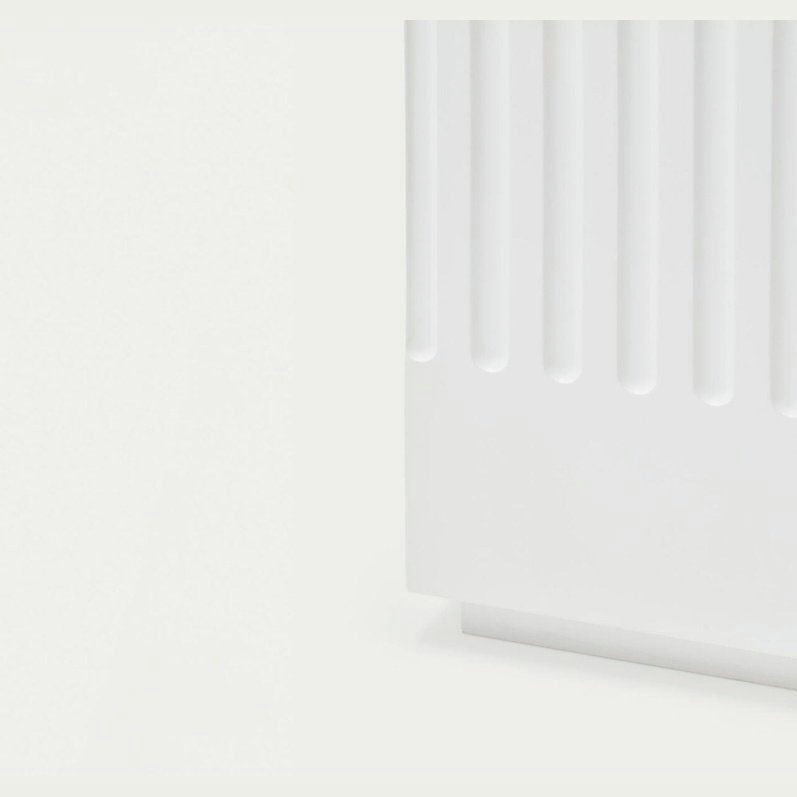 La Cómoda en MDF con 2 Puertas y 2 Cajones Doric 2P2C presenta un panel texturizado blanco con ranuras verticales sobre un fondo claro, mostrando un diseño minimalista que realza cualquier espacio.